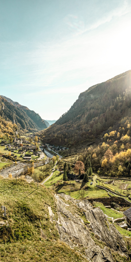 Wanderer vor der Kapelle Santa Maria Maddalena al Calvario im Calancatal mit Blick auf das herbstliche Tal