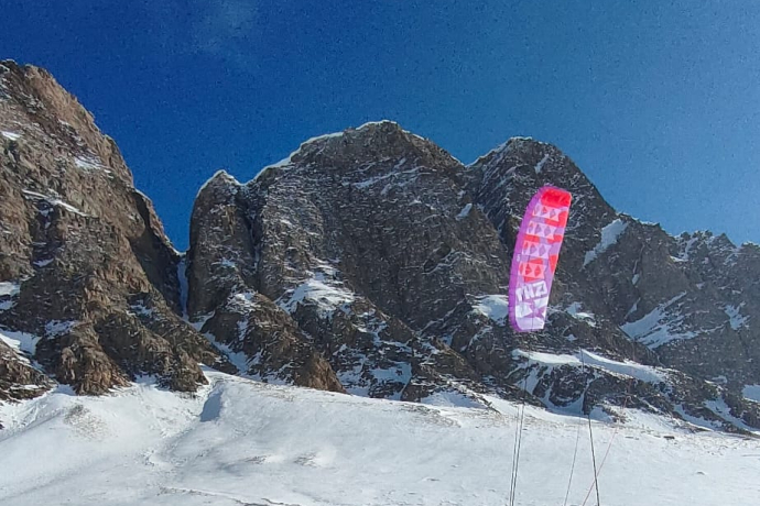 Con l'aiuto di una vela si possono raggiungere posti altrimenti difficilmente accessibili. Un pilota raggiunge le pendici del Piz Uccello con lo snowkite