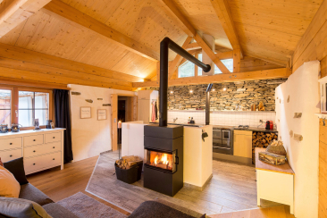 Gemütlicher Wohnraum mit Kamin und Blick in die Küche der Berghütte Pundelon